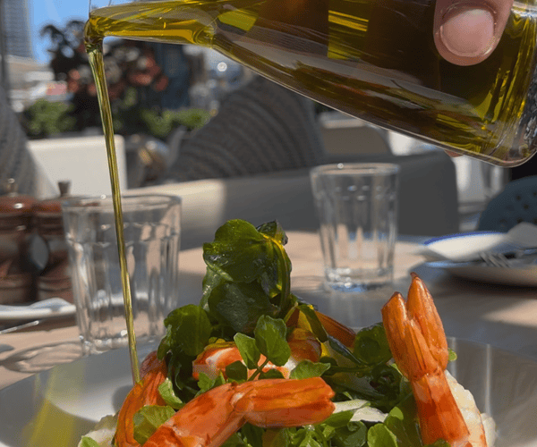 Extra Virgin Olive Oil especially imported for Georges Mediterranean is poured over a prawn salad